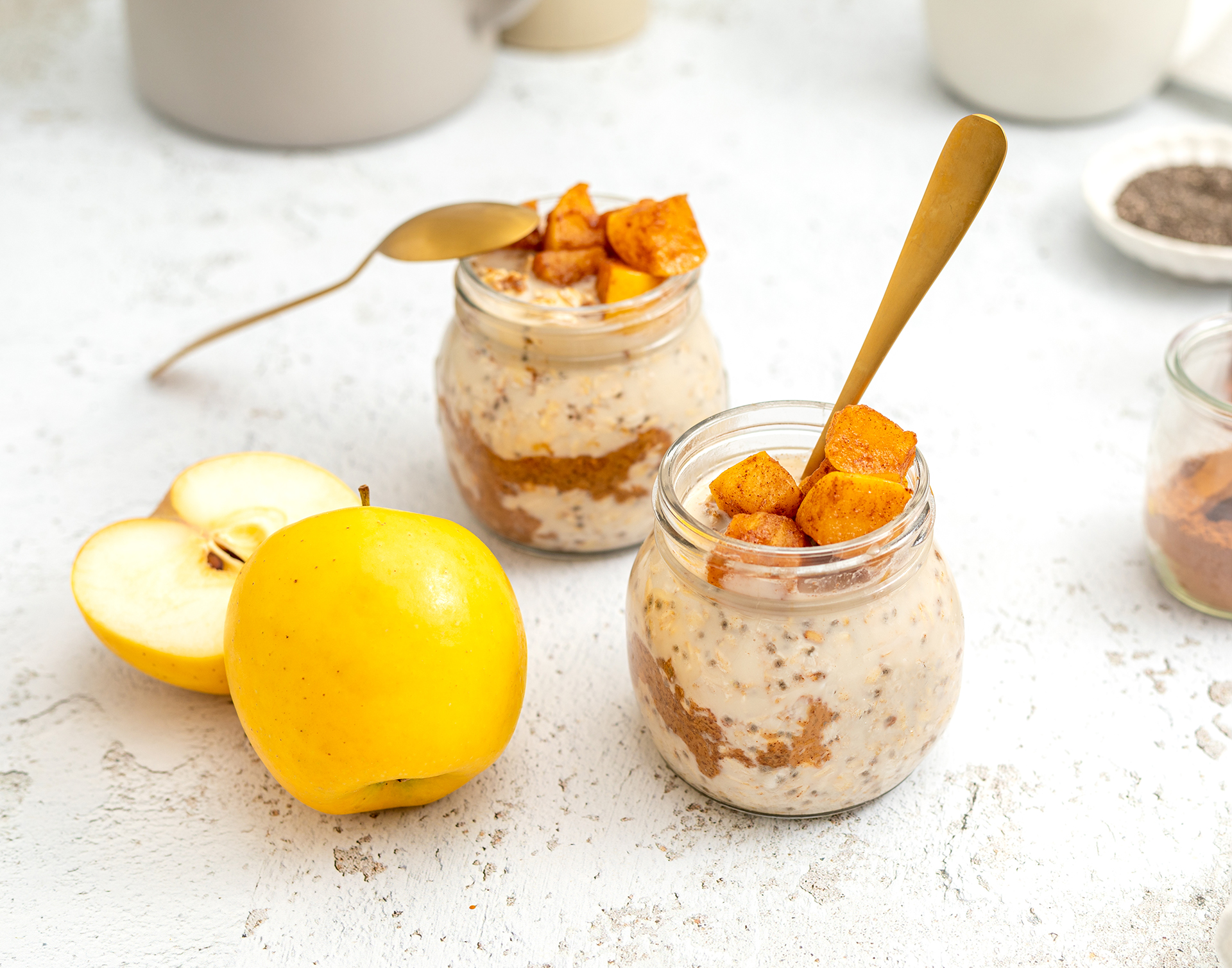 Image of two glasses filled with oats with two yellow Opal apples next to them. 