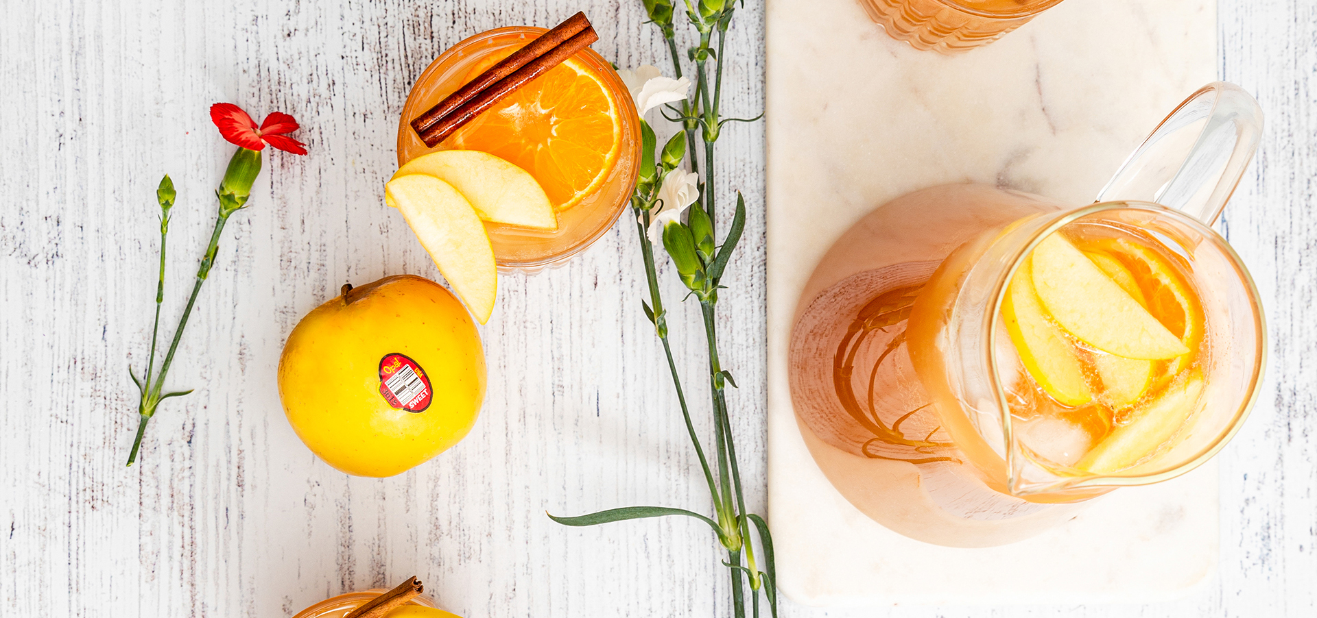 A view of a orange cider punch from above with fresh Opal apples. 